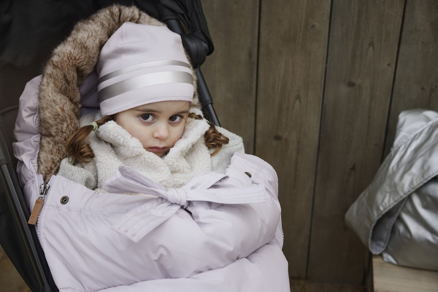 Baby in stroller cozy in lavender Fußsack, ideal for winter warmth and style, beloved by design-oriented parents.