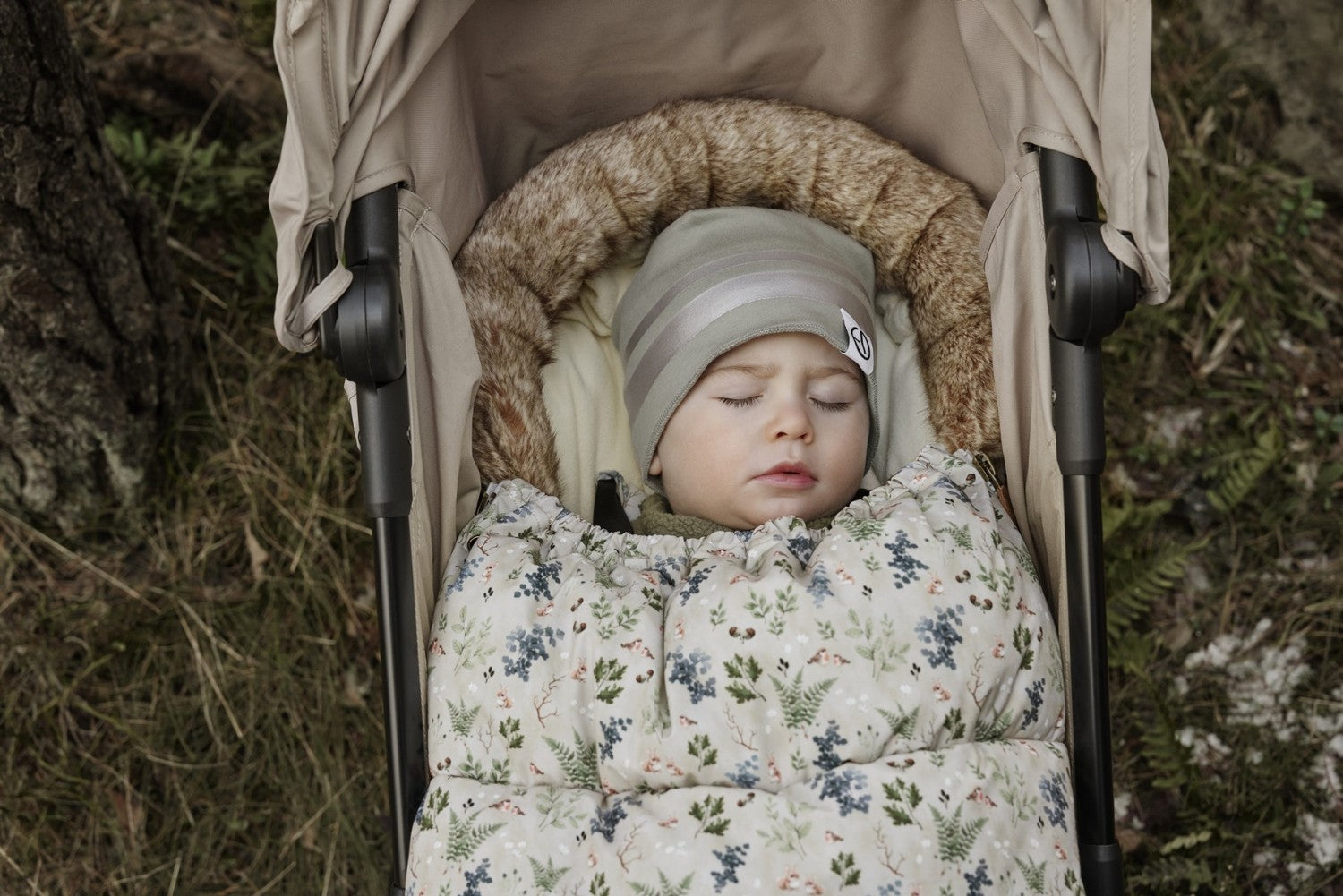 Baby sleeping in stroller with Fairytale Forest Fußsack, featuring thick padding and floral design for winter warmth and style.