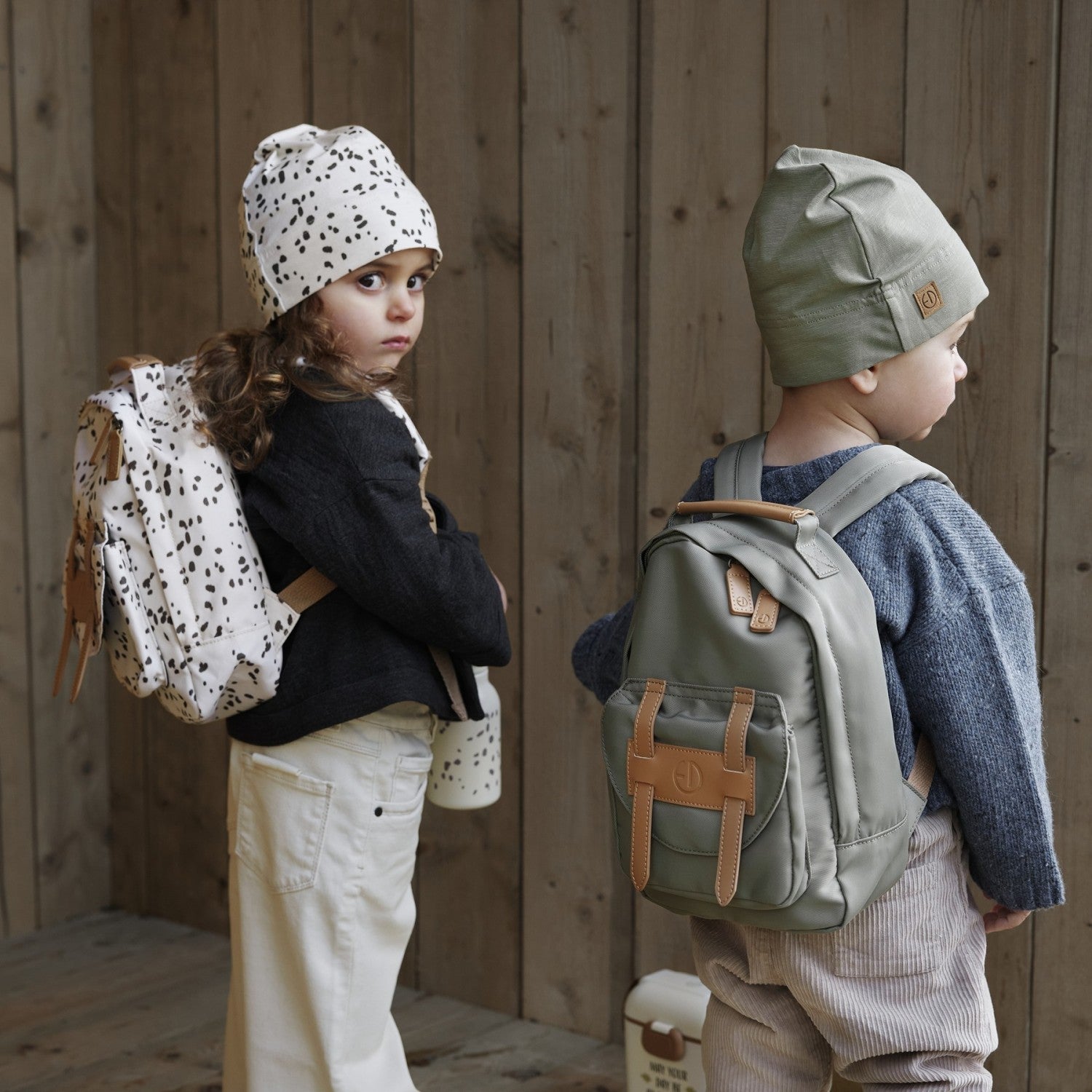 Two children wearing stylish backpacks, including a Dalmatian Dots design, perfect for young adventurers and everyday use.