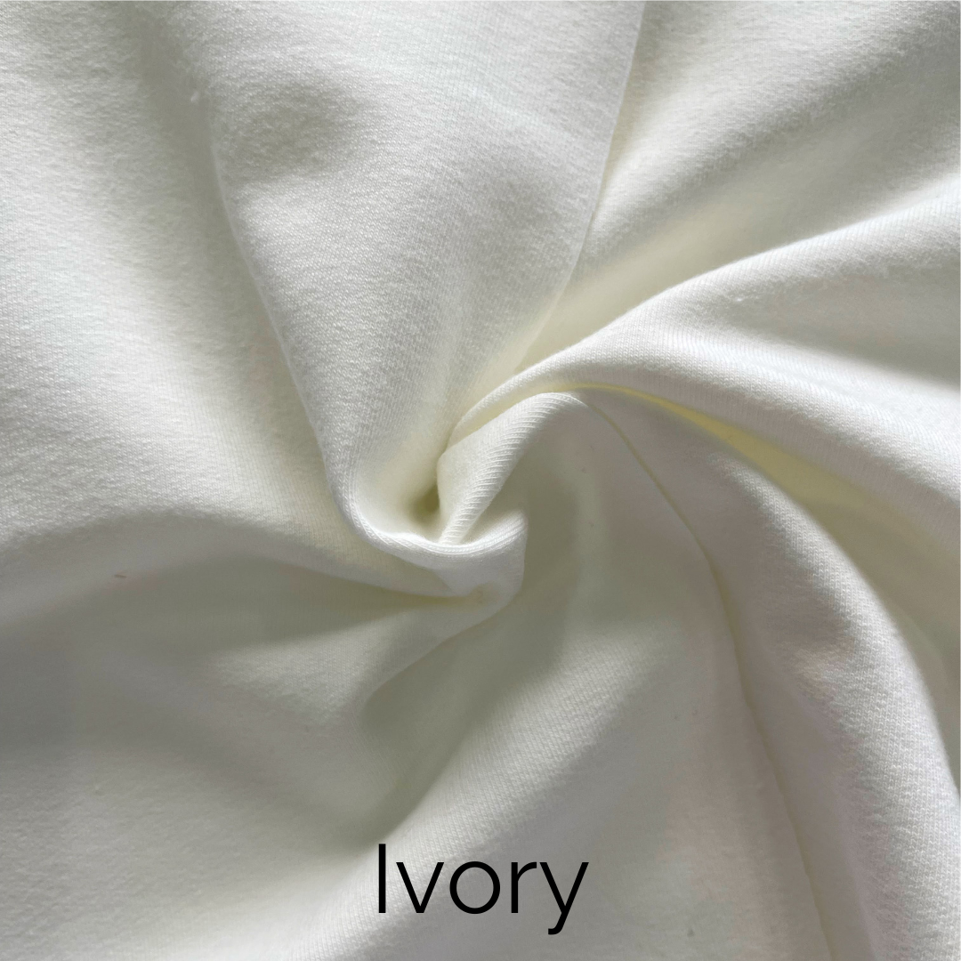 Close-up of ivory jersey fabric showcasing soft texture and drape.