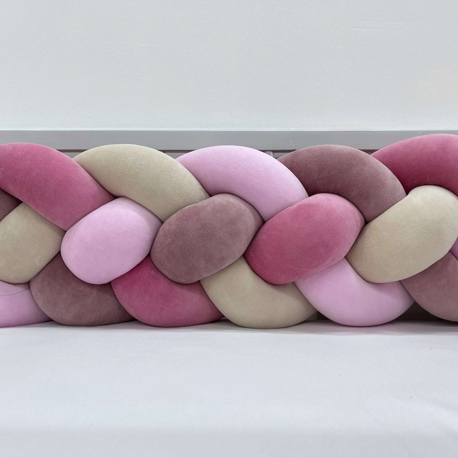Bettschlange Leif in sanften rosa- und beigen Farbtönen, weich gepolstert für Komfort im Kinderzimmer.